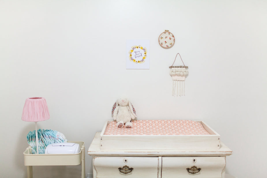 Antique drawers with changing table top, nursery decor, pink bedding, lamp, and wall accessories