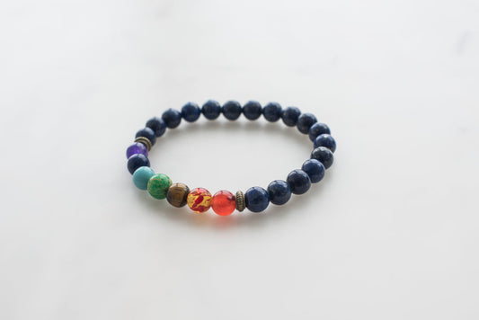 7 Chakra Bracelet with colorful beads including dark blue lapis lazuli, purple, green, tiger's eye, and red carnelian stones.