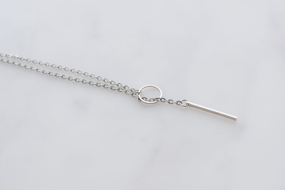 Silver threader necklace with delicate chain and hanging bar detail on white background.