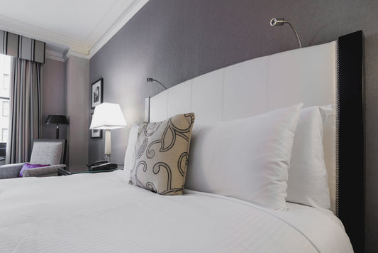 Crisp white bed clothes on luxury hotel bed with decorative pillow and reading lamps in modern bedroom interior