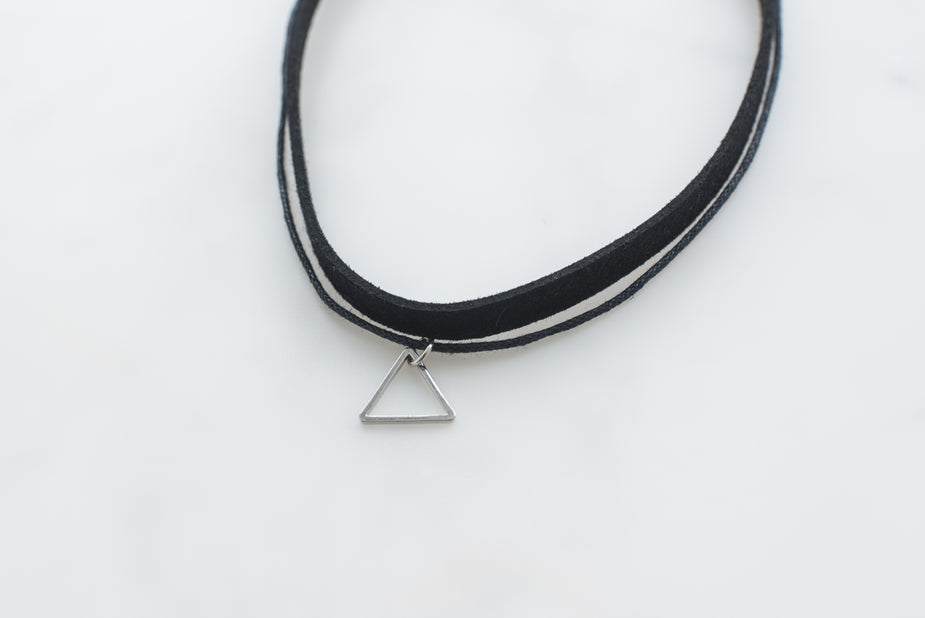 Black leather choker necklace with small silver triangle pendant on white background