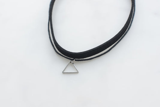 Black leather choker necklace with small silver triangle pendant on white background