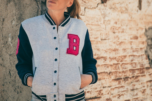 Classic Varsity Top in grey and navy with red B patch, worn by model against brick wall