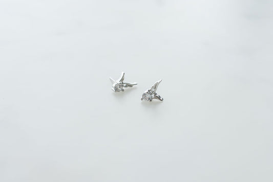 Guardian Angel Earrings: delicate silver stud earrings featuring angel wing design with sparkling crystals on white background.