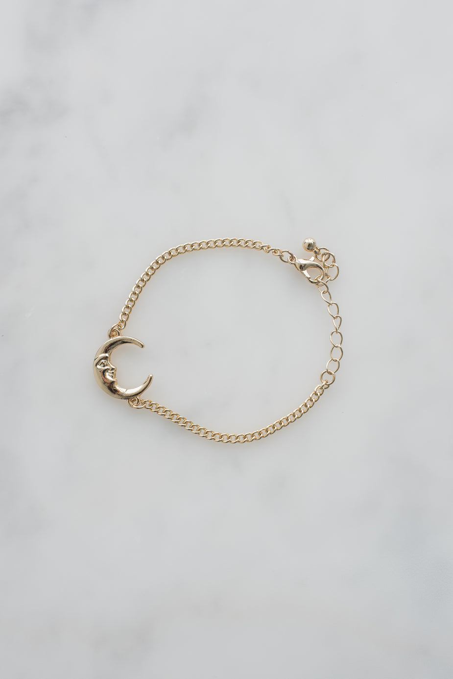 Gold moon charm bracelet with curb chain and adjustable clasp on white background