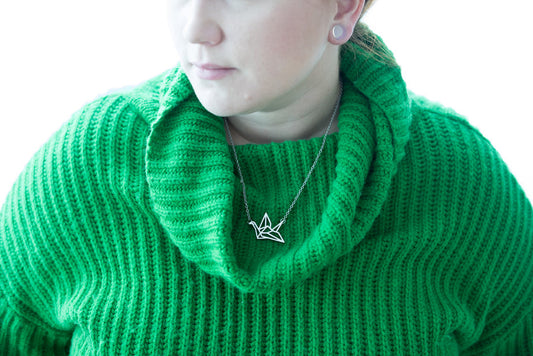 Silver Origami Crane Necklace worn with green ribbed sweater, delicate paper crane pendant on chain