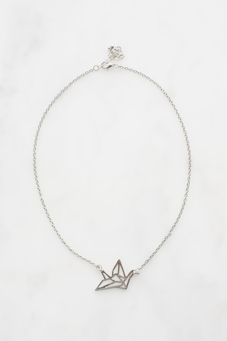 Delicate silver origami crane necklace pendant on thin chain with clasp against white background.