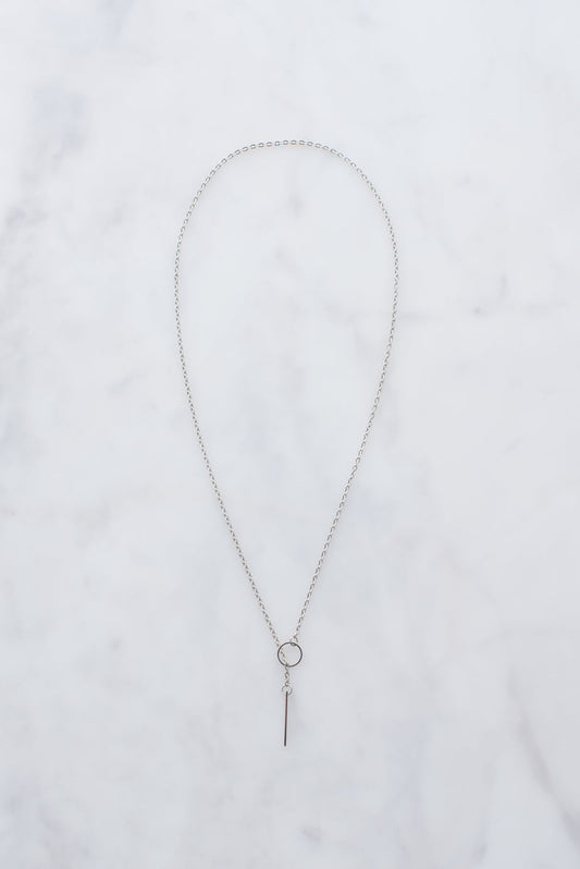 Silver threader necklace with delicate chain and hanging bar pendant on white marble background.