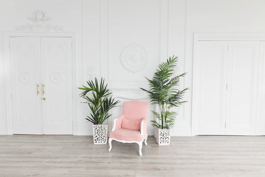 Pink armchair with white frame in modern room with potted plants and white doors
