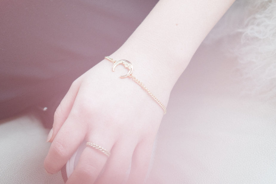 Moon charm bracelet worn on wrist, delicate rose gold chain with crescent moon pendant detail