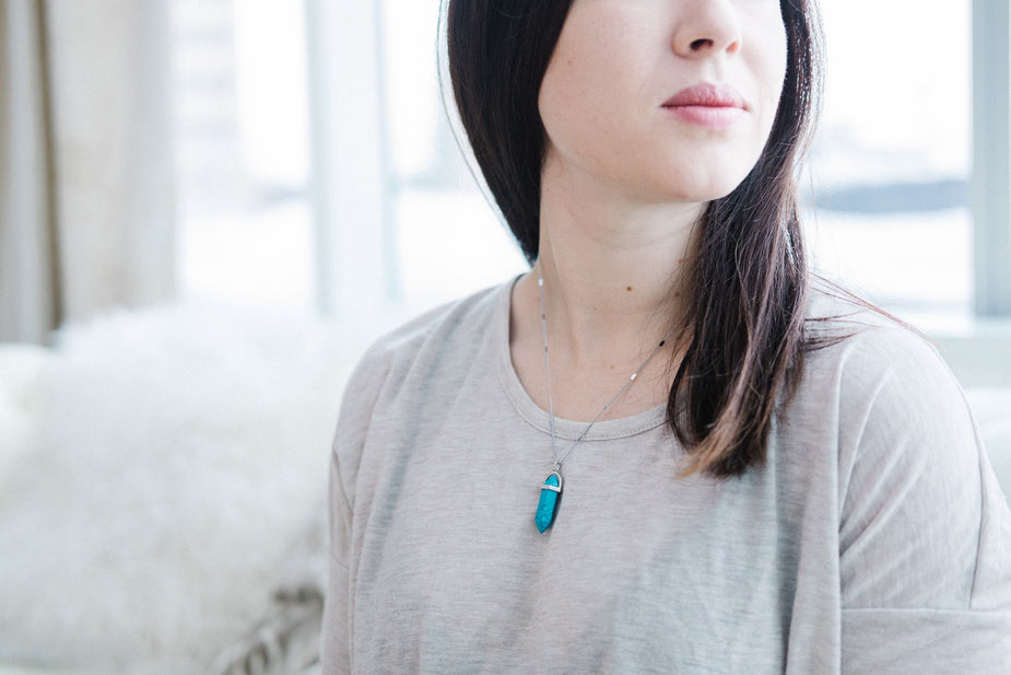 Blue turquoise gemstone necklace pendant worn by woman in casual beige t-shirt